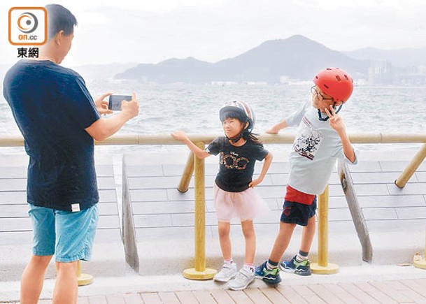 颱風下有市民帶同小朋友到海旁拍照。（李志湧攝）