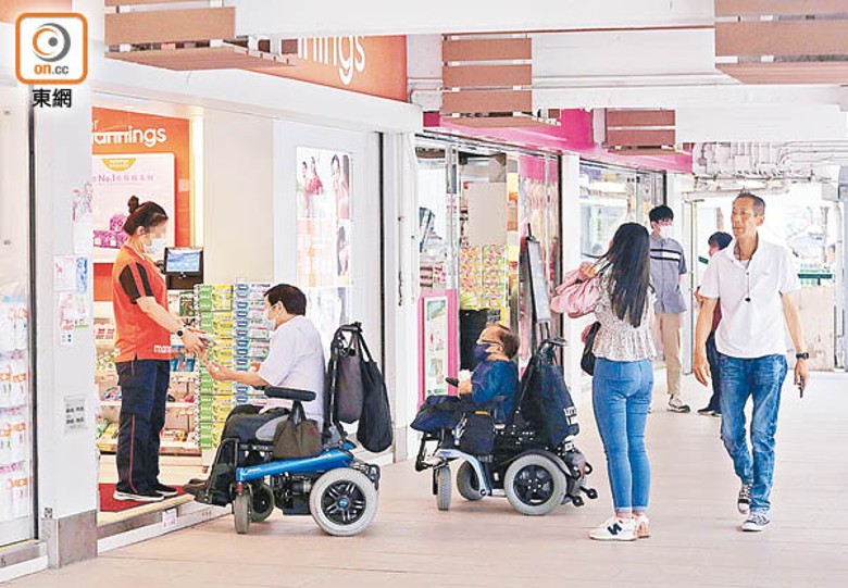 有連鎖用品店職員拿着數包喉糖，走出店外讓輪椅使用者揀選。