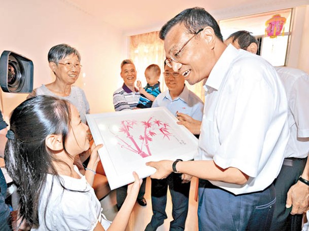 李克強（右）探訪香港家庭，接受戶主孫女繪畫的圖畫。