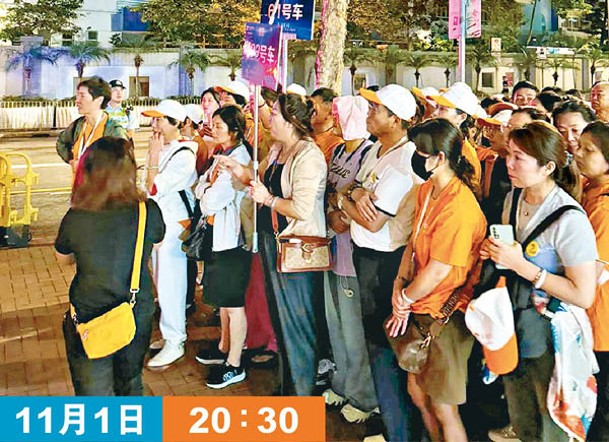 身穿橙衣、戴着白帽的旅客分每行約10人排隊，分批進入食肆。