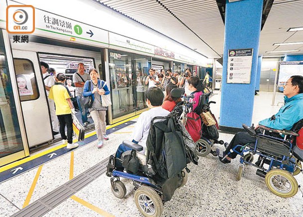 港鐵職員正協助殘疾人士進車廂。