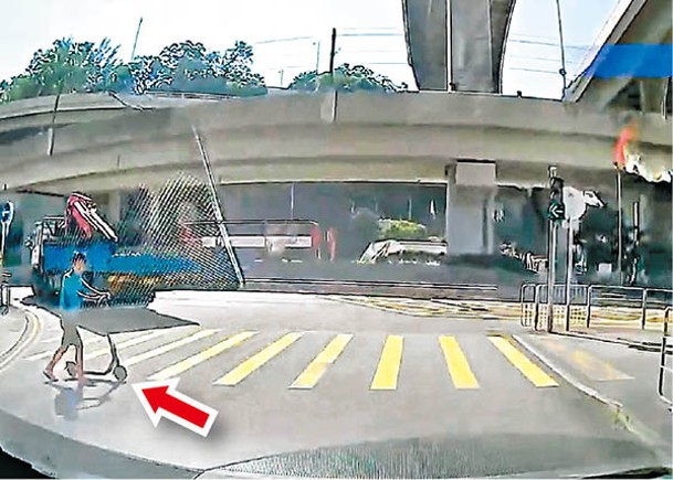 推滑板車男子（箭嘴示）不依交通燈號過馬路。