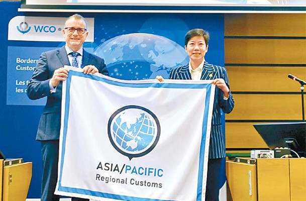 何珮珊（右）從澳洲邊防局局長Michael Outram（左）手上接過象徵世界海關組織亞太區副主席的旗幟。