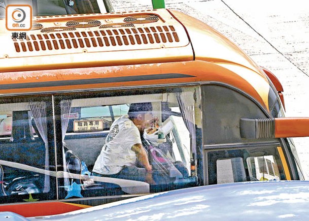有旅遊巴司機在車上享用飯盒。