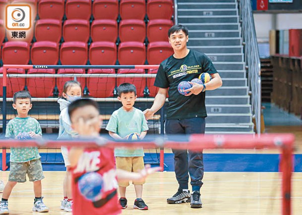 謝永輝（右）擔任活動教練，讓小朋友接觸手球。