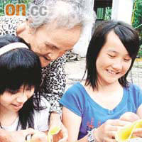 巫金菊摟着孫女曾雲欣，教她如何包裝五月桃。	（本報台北傳真）