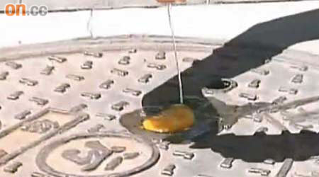 內地記者以金屬渠蓋煎蛋，測試路面溫度。	（電視畫面）