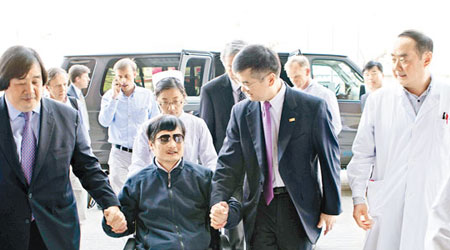 陳光誠坐着輪椅，與駱家輝（右）手握手進入醫院。（互聯網圖片）