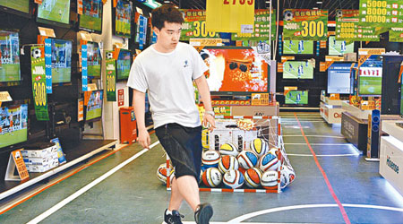 北京商家推出「買電視送足球」促銷活動，店員大騷腳法。（中新社圖片）
