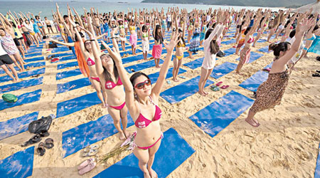 千名女參加者身穿比堅尼泳衣，在沙灘上進行瑜伽表演。（中新社圖片）