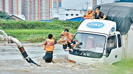 貴州都勻市有貨車被洪水圍困，拯救人員逐一救出被困者。（中新社圖片）
