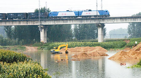 由於暴雨阻斷交通，村民被迫經鐵路橋渡河。（中新社圖片）