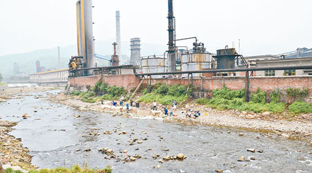 工作人員在工廠對開河流堵截污染物。（中新社圖片）