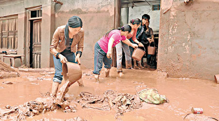 四川瀘沽鎮民眾在清理門前淤泥。（中新社圖片）