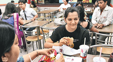 圖中的印度女子正在食用素漢堡。（資料圖片）