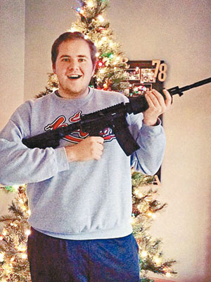 一名男子舉起AR-15步槍，在聖誕樹前笑不攏嘴。