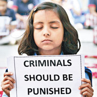 一女童手持「罪犯必須懲治」的標語。