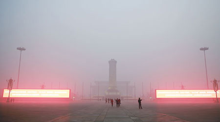 遊客在遭受嚴重霧霾籠罩的天安門廣場遊玩。（中新社圖片）