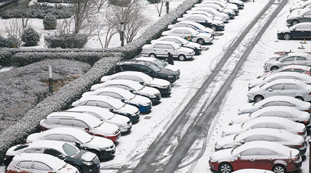北京昨日降雪，街頭停泊的多輛汽車被白雪覆蓋。（中新社圖片）