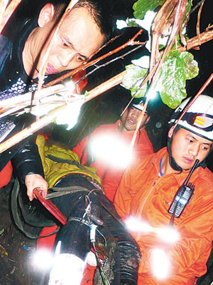 救援人員於客貨車墮崖現場救出傷者。（中新社圖片）