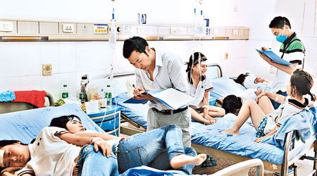 眉山市患病學生在病床休息，工作人員到場詢問他們的病情。（中新社圖片）