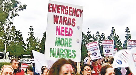 參與罷工的護士舉起示威標語，要求醫院增聘人手。