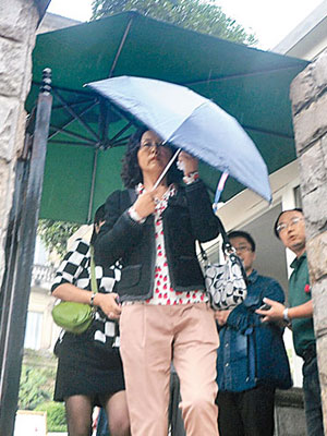 雷政富的妻子離開法院時用傘遮面。（中新社圖片）