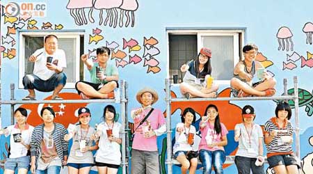 台西藝術村的各國義工，與當地青少年在彩繪牆前留影。（郭良傑攝）