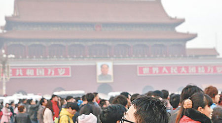 一名男子戴着口罩在北京天安門廣場等待觀看降旗儀式。（中新社圖片）