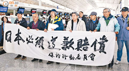 羅堪就（前排右五）及陳妙德（前排右四）昨往北京前，在本港機場拉起「日本必須道歉賠償」的抗議橫額。（盧志燊攝）