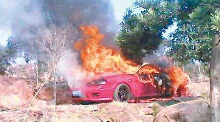 紅色跑車被大火包圍，車窗上掛着一具男屍。（互聯網圖片）