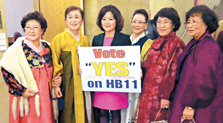 里士滿的韓裔美籍婦女手持標語，慶祝法案通過。（互聯網圖片）