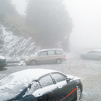 合歡山的馬路和車頂均鋪上一層白雪。（中央社圖片）