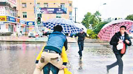 年輕女子孭起男友走過水浸的馬路。（互聯網圖片）