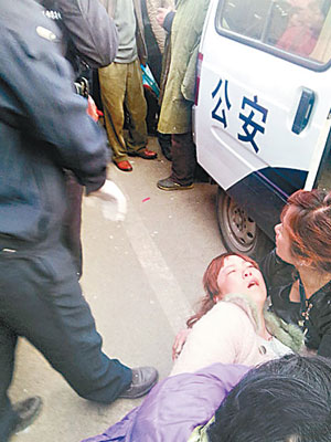 疑被警員打傷的懷孕攤販倒在警車旁。　（互聯網圖片）