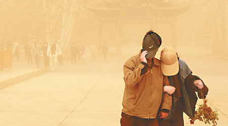 甘肅 <br>甘肅敦煌受強沙塵暴吹襲，民眾要用帽子擋沙。（中新社圖片）
