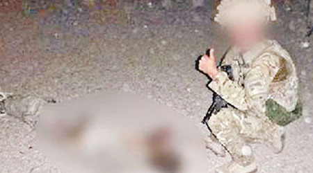 一名英兵在塔利班武裝分子屍體旁，豎起拇指拍照。（互聯網圖片）
