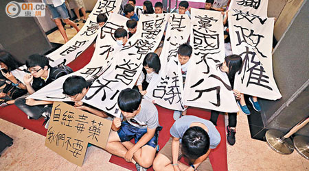 學生手持寫滿抗議口號的白布靜坐。