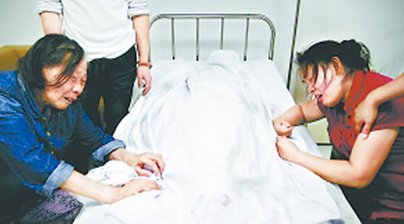 孫亮的身體用白布遮蓋，其祖母（左）和母親（右）伏屍痛哭。（互聯網圖片）