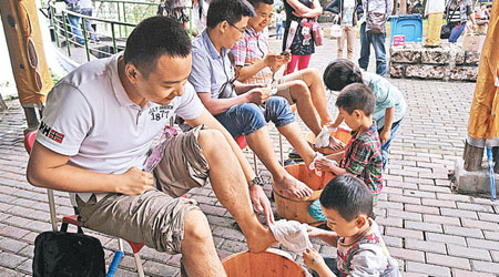 重慶有團體舉辦感恩父愛公益活動，兒女為父親洗腳。（中新社圖片）