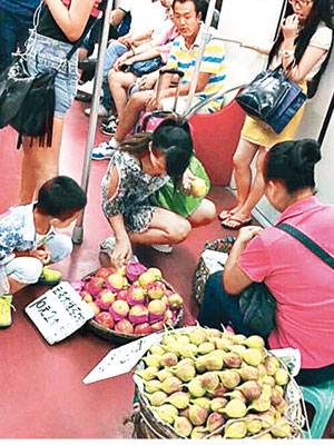 女小販（右）在地鐵車廂內賣水果，有乘客蹲下挑選。（互聯網圖片）