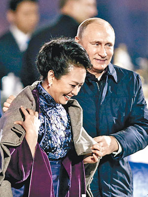 俄羅斯總統普京站起來，為身旁的習近平夫人彭麗媛披上毛氈。（中新社圖片）