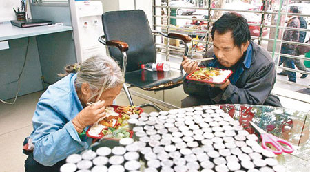 殘疾夫婦在銀行內吃飯盒等待點算硬幣。（互聯網圖片）