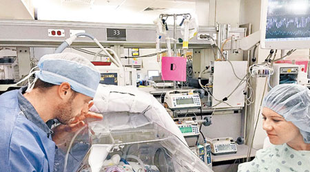 巴斯比（右）與丈夫（左）在醫院看着剛出生的女兒。（互聯網圖片）