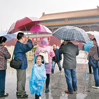 有民眾冒低溫在天安門城樓前駐足賞雨。（中新社圖片）