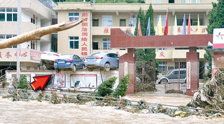 雲南昭通出現嚴重水災，有車輛被沖上牆頂（箭嘴示）。（中新社圖片）