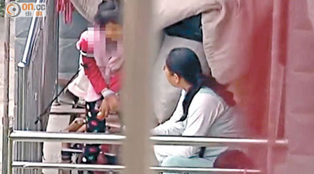 兩名寄養的殘障兒童被劉家用繩拴在露台。（電視畫面）