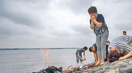 家屬在江邊拜祭哀悼遇難親人，場面淒戚。（互聯網圖片）