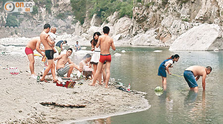 有遊客在河邊燒烤及戲水。