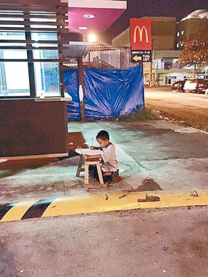 卡比拿利用快餐店燈光，在路邊做功課。（互聯網圖片）